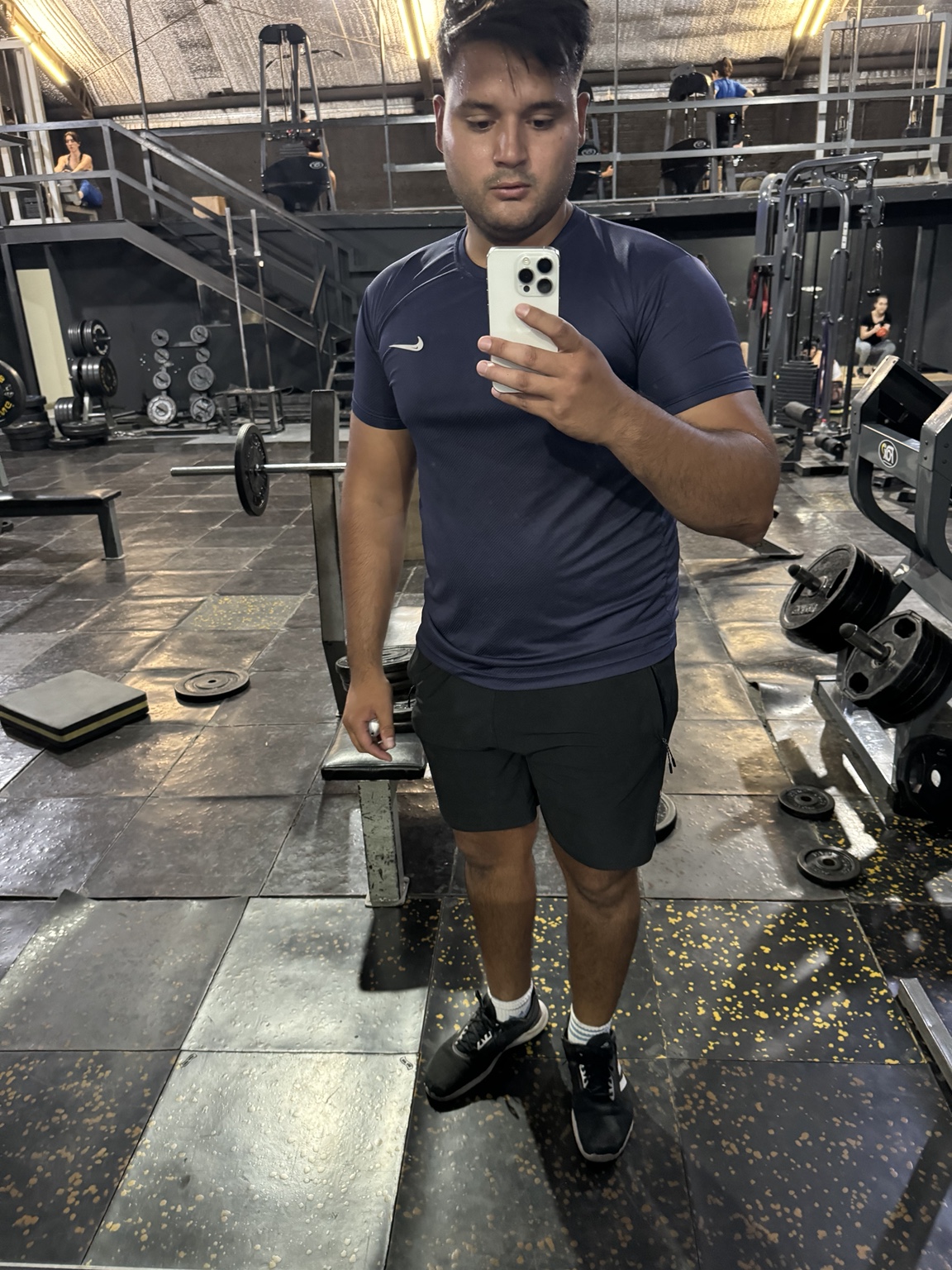 ALEN frente al espejo del gimnasio con camiseta azul oscuro y pantalón corto negro.